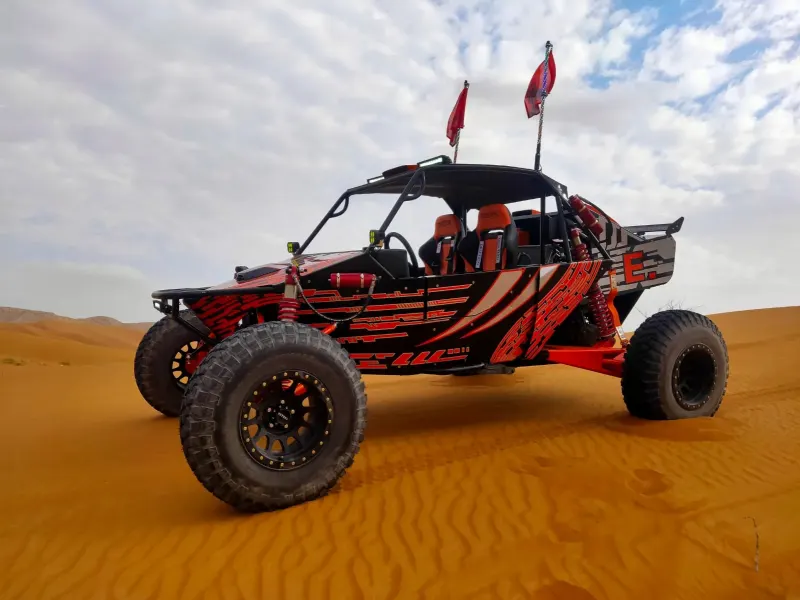 Red and black dune buggy with flags on the sand