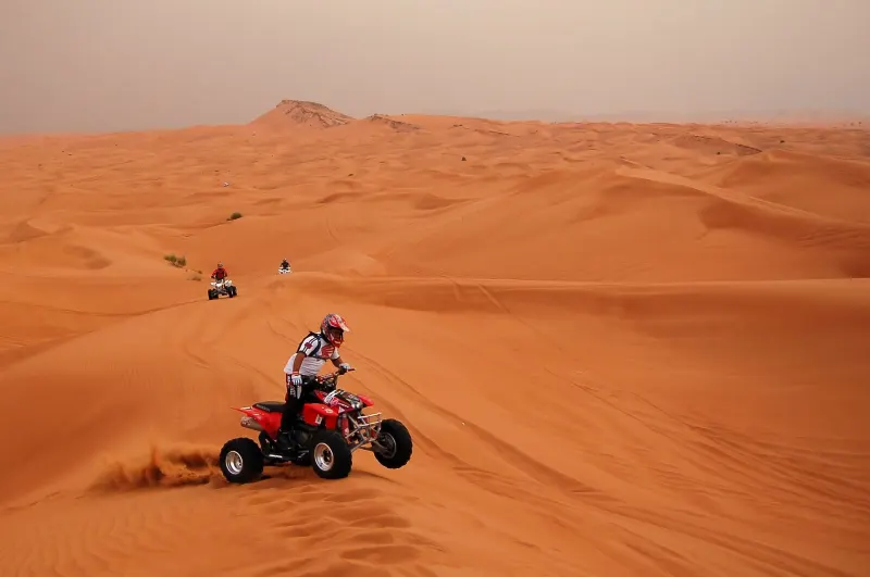Quad bikes riding over the red dunes of the Dubai desert