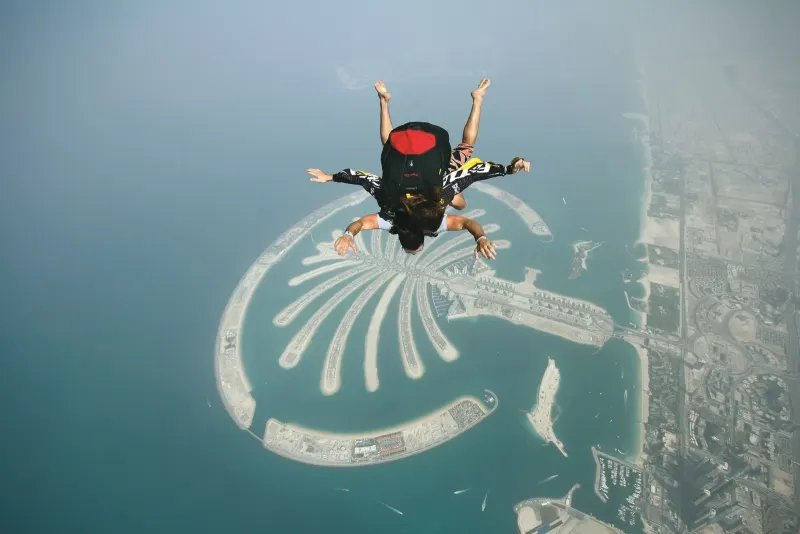 Tandem skydivers in freefall above the Palm Jumeirah