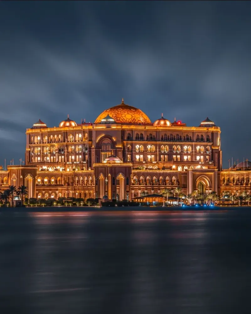 Emirates Palace lit up at night across the water