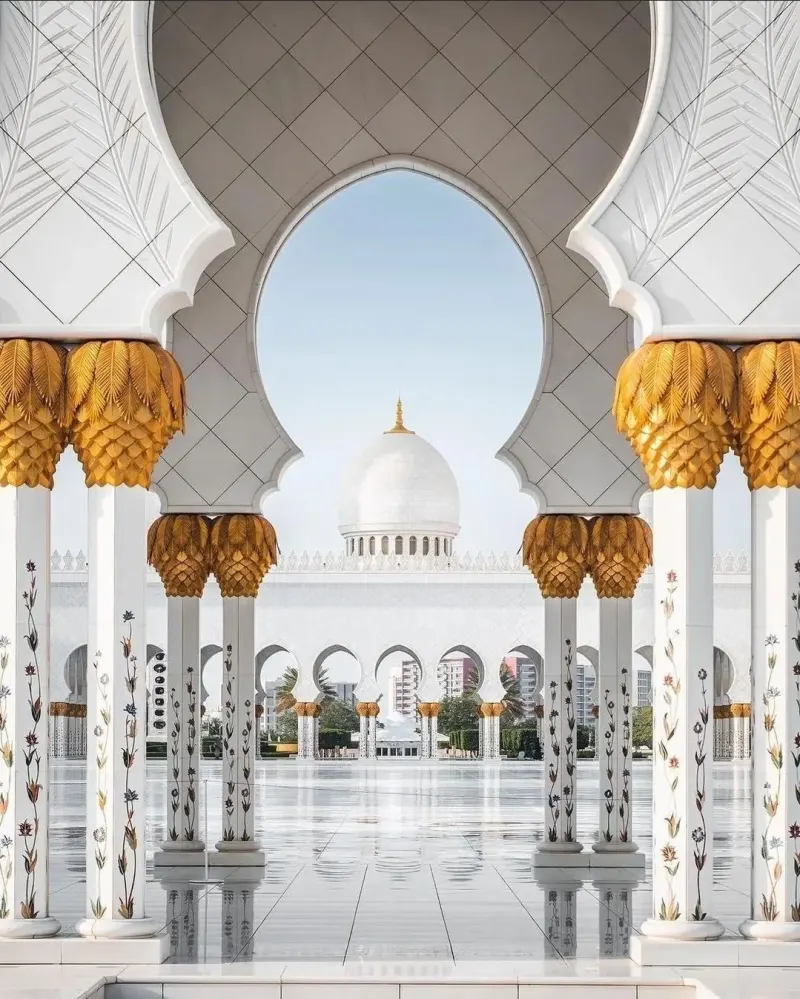 Gilded columns and an arch framing a dome of the Sheikh Zayed Grand Mosque