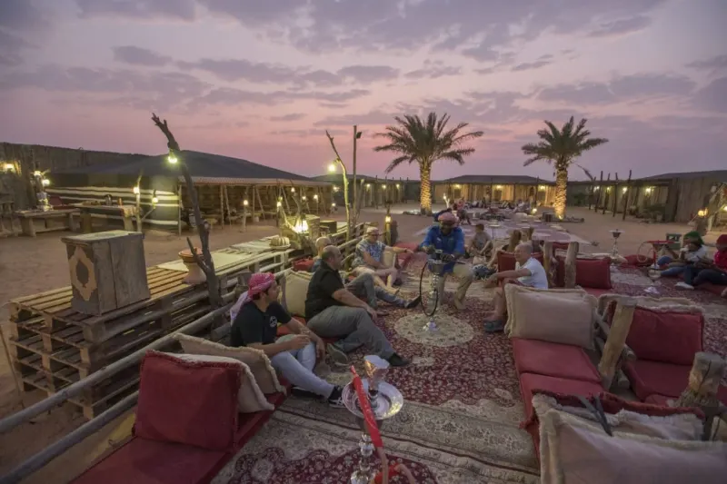 Guests relaxing on cushions at a desert camp at dusk
