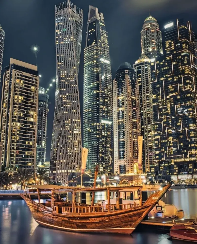 Illuminated wooden dhow among the Dubai Marina towers at night