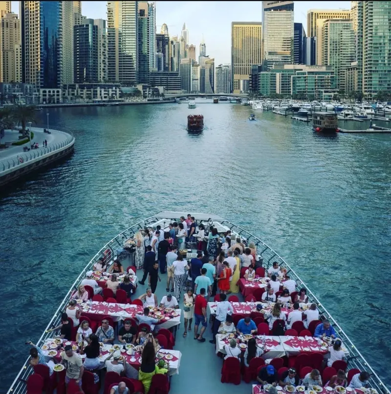 Guests at dinner tables on the deck of a cruise boat in Dubai Marina