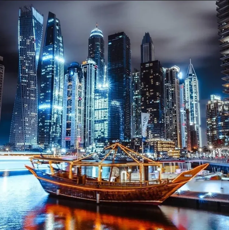 Wooden dhow in front of the lit-up Dubai Marina skyline