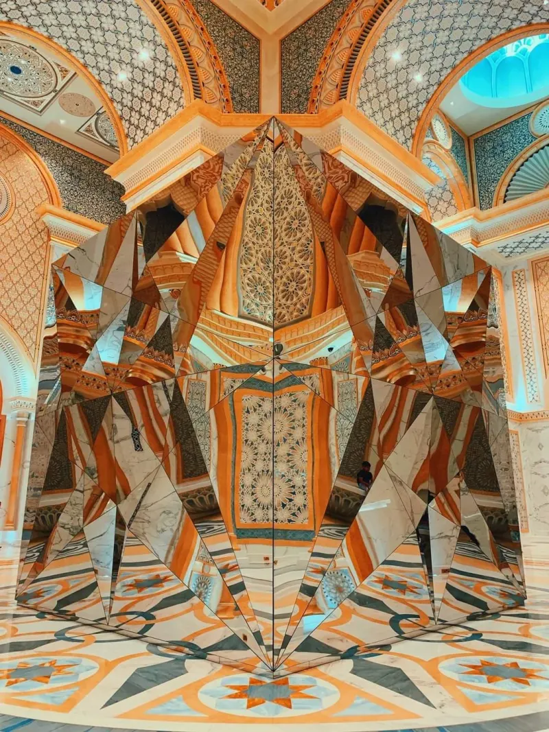 Mirrored sculpture reflecting a decorated hall of Qasr Al Watan