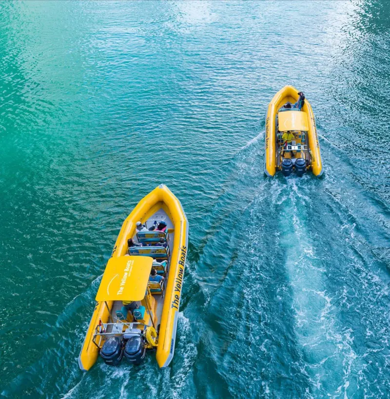 Two yellow speedboats on turquoise water, seen from above