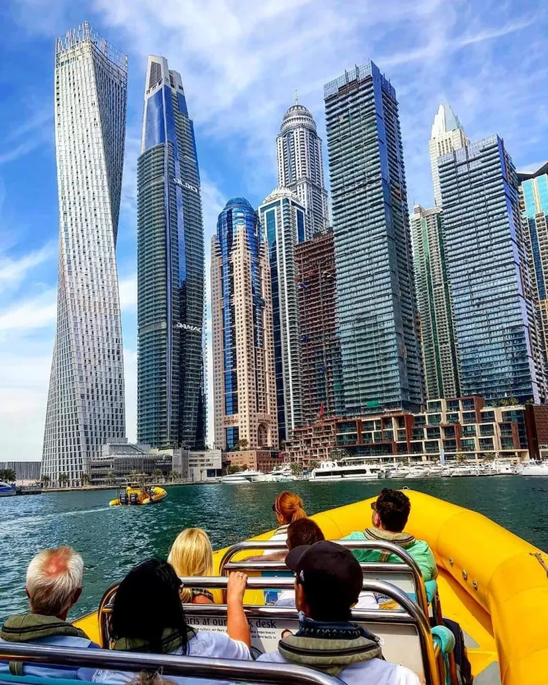 Passengers on a yellow speedboat among the Dubai Marina towers